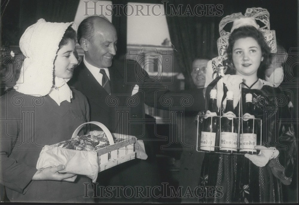 1957 Press Photo Girls in Traditional Dress Present Oysters &amp; Wine to Mr. Ruais-Historic Images