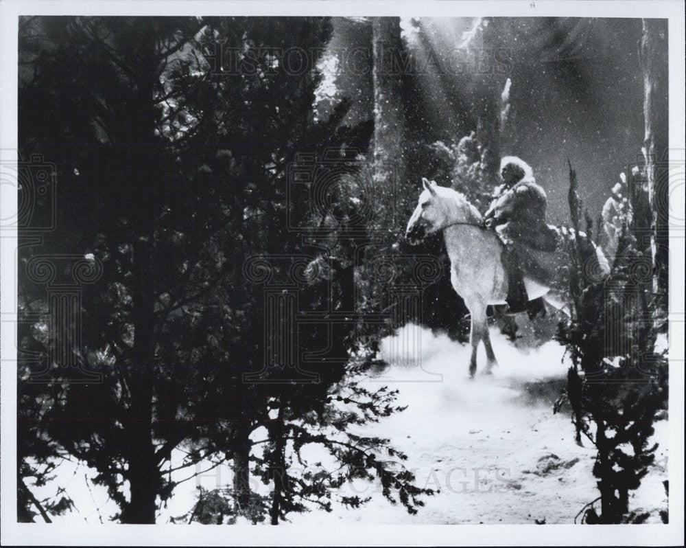 Press Photo in a snow land with a man riding a white horse - Historic Images