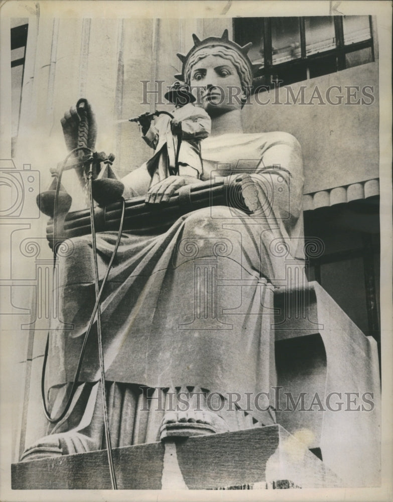 1958 Worker stands in the lap of justice  - Historic Images