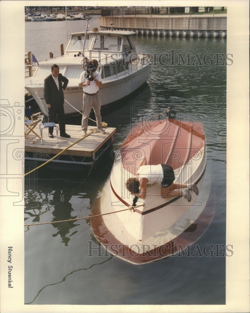 1990 An over turned boat is inspected in Be - Historic Images