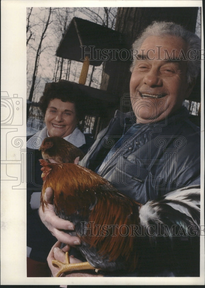 1993 Man holds live chicken on a farm - Historic Images