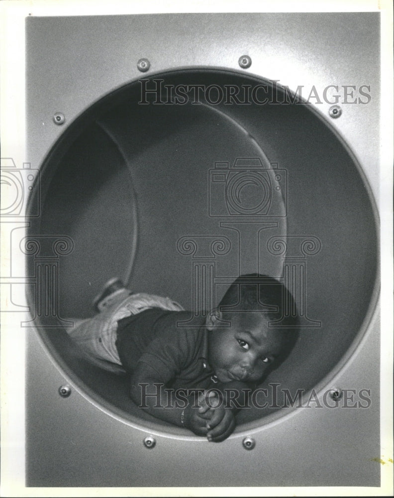 1990 Toddler rests in tunnel at day care - Historic Images