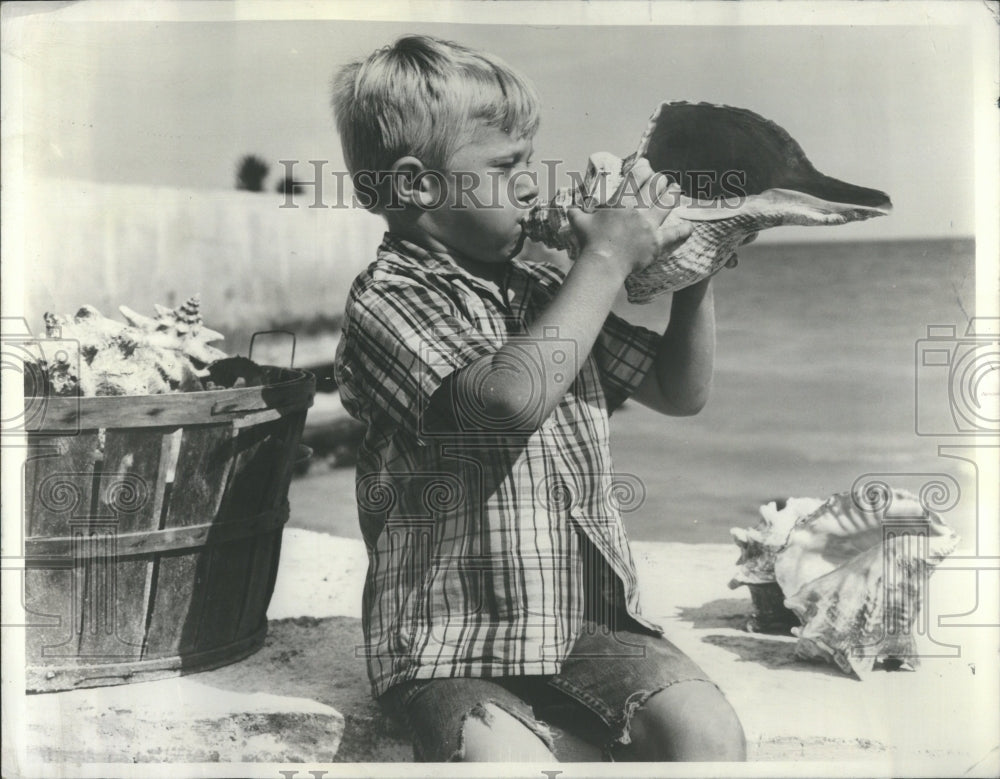 1972 Young boy tunes for conch shellblowing - Historic Images