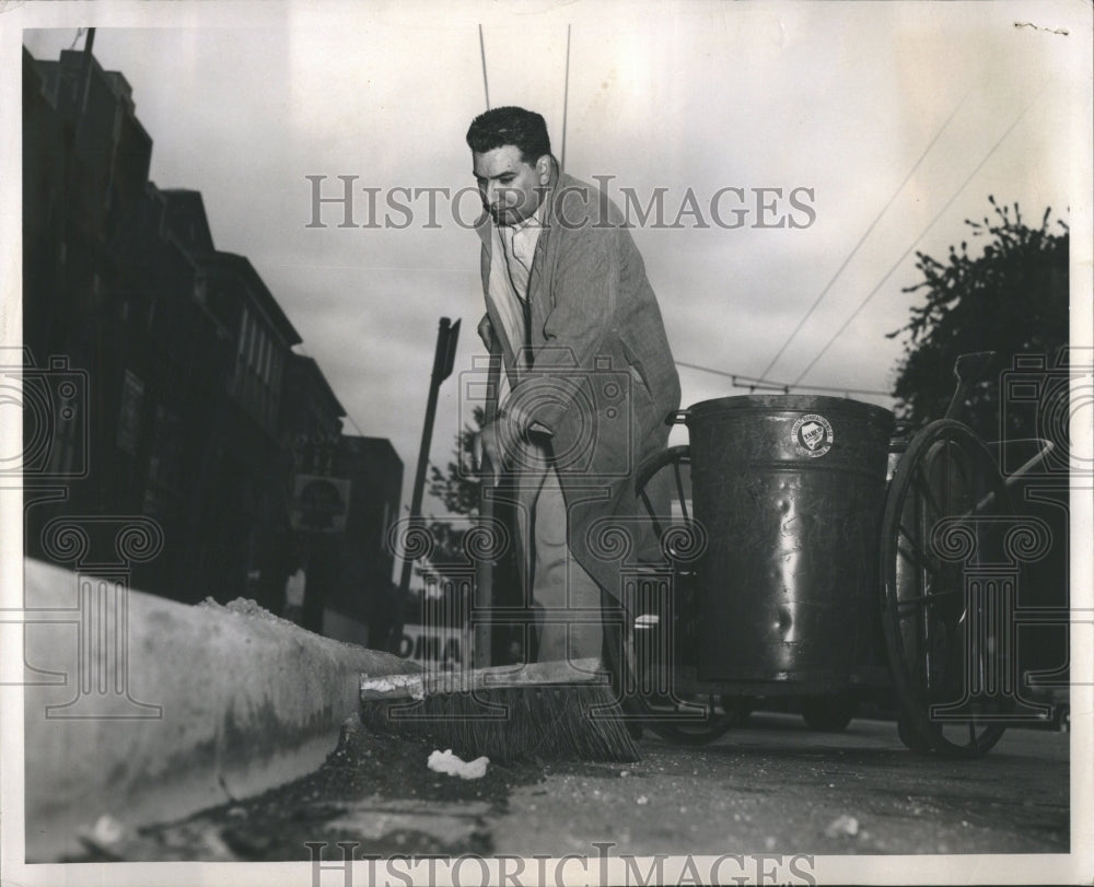 1957 Man with broom sweeps street - Historic Images