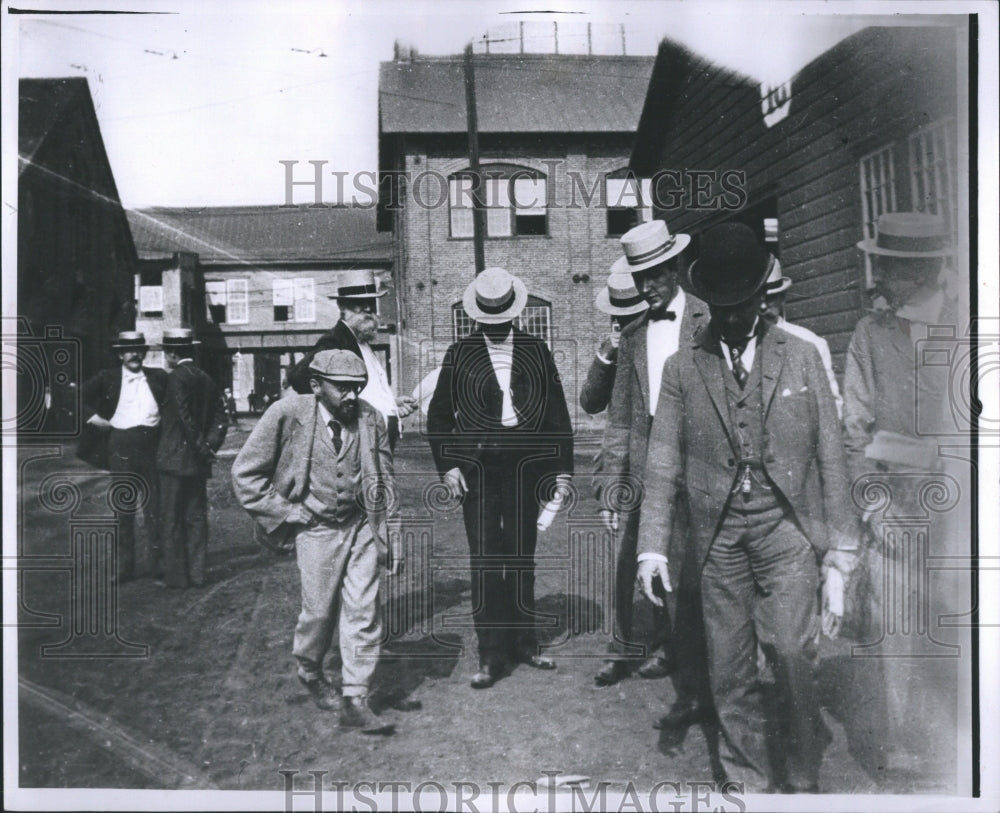 1957 Press Photo Men in suits and hats walking in town