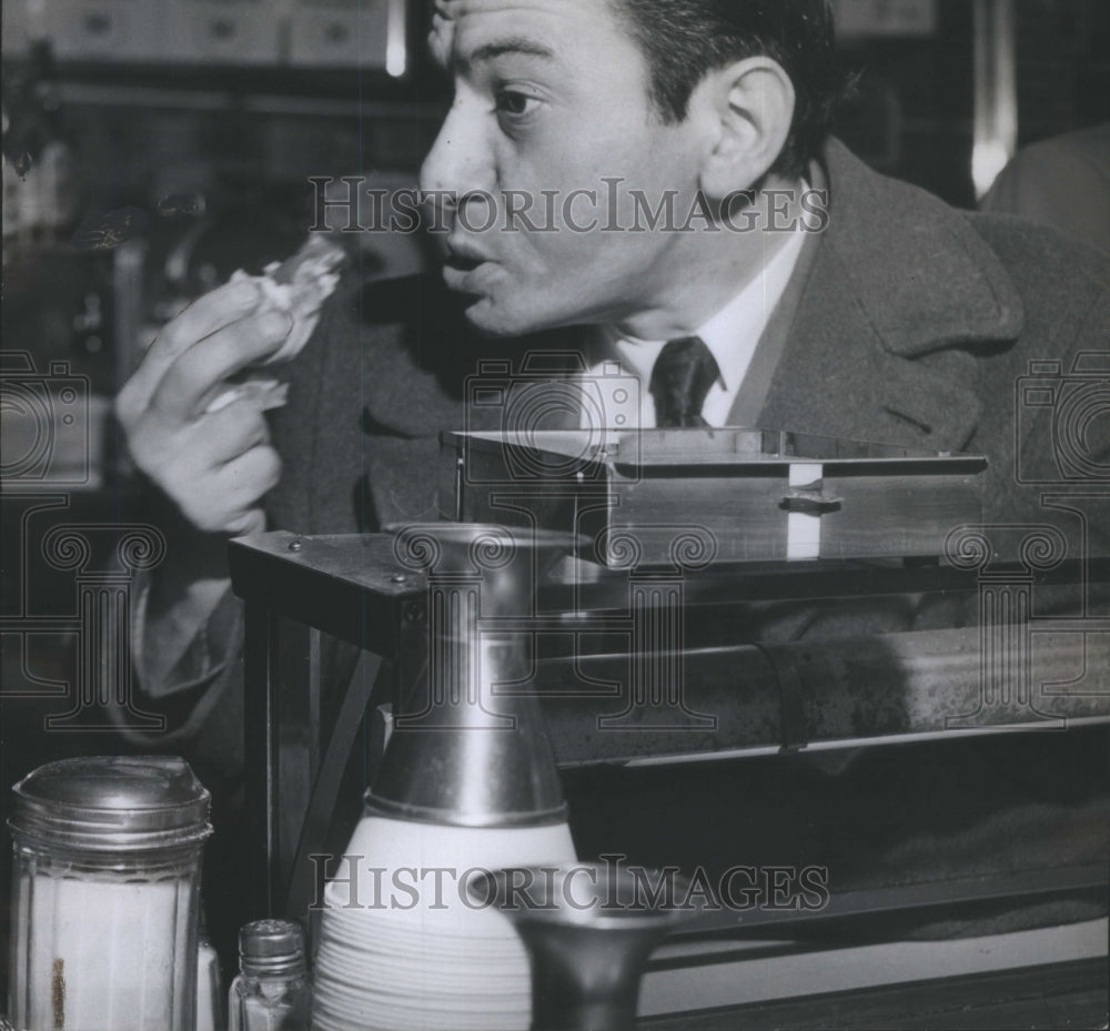 1950 Man eating a hotdog in a restaurant - Historic Images