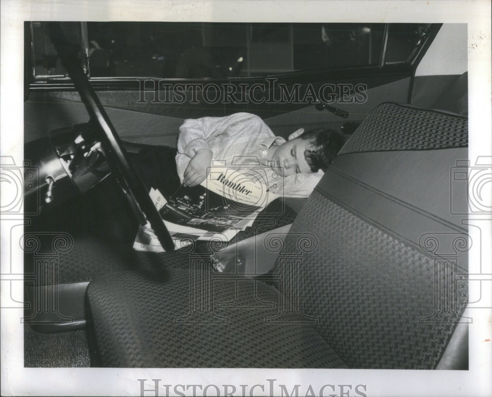 1959 Boy fall asleep in new car at Autoshow - Historic Images