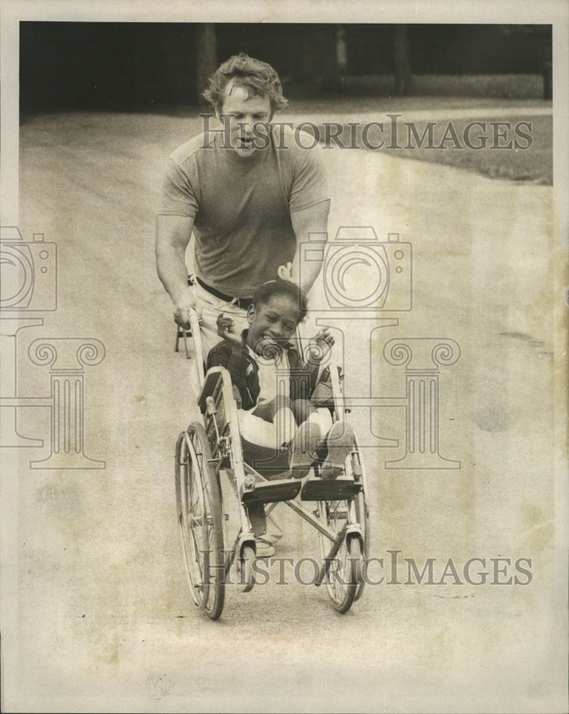 1975 Press Photo Man Running With Girl In Wheelchair - RRW29009 - Historic Images