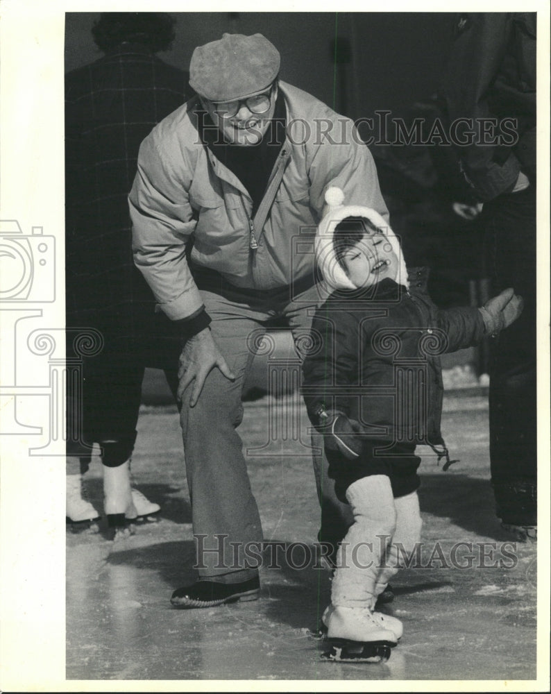 1986 Press Photo Man kid Christmas ice skating spinning - RRW40611 - Historic Images