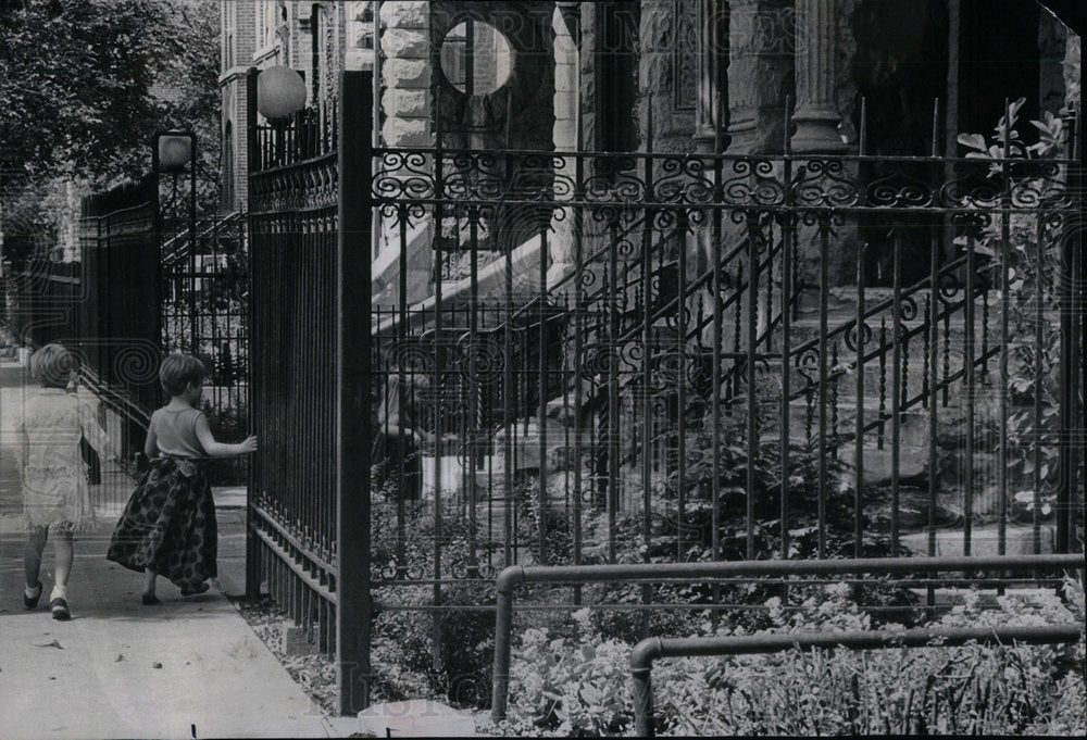 1967 Iron fence being hold by a child - Historic Images