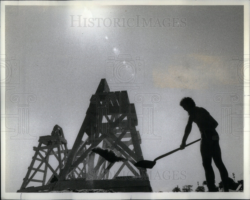 1982 Lifeguard shovels sand on a slow day - Historic Images