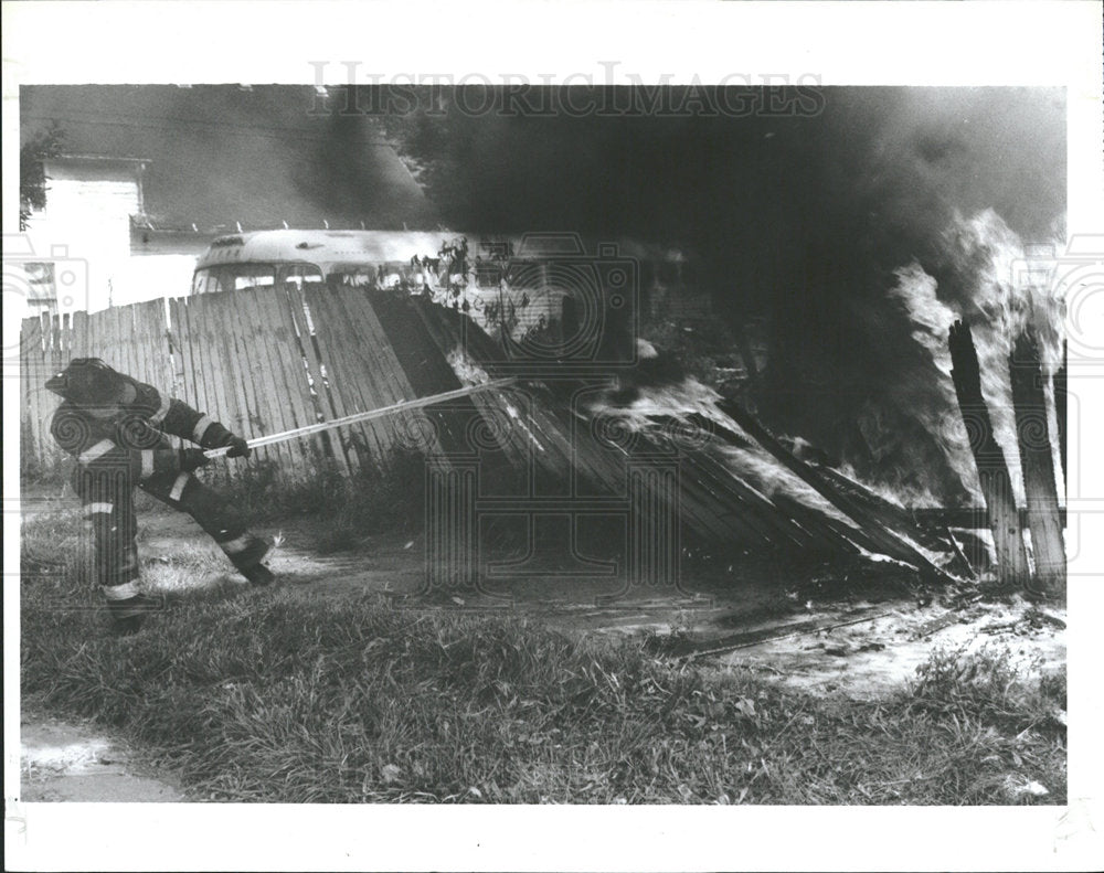 1989 Press Photo Fireman Pulling Down Burning Fence - Historic Images