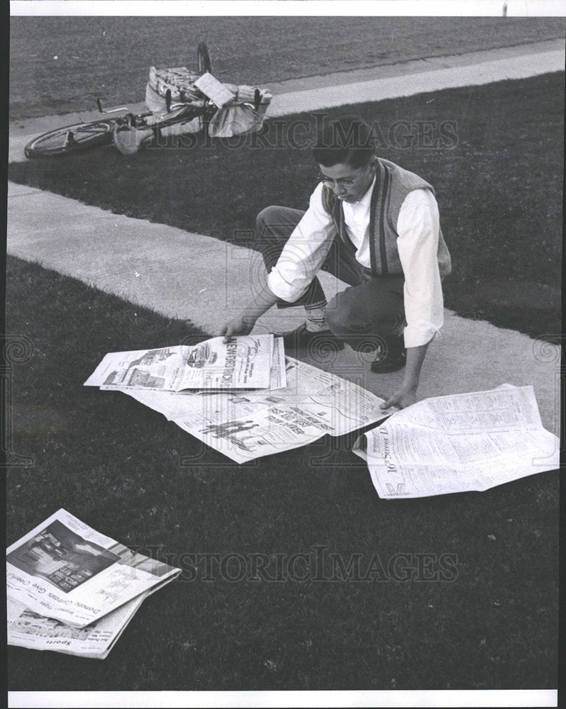 1959 Press Photo Newspaper Boy Picking Up Dropped Paper - Historic Images