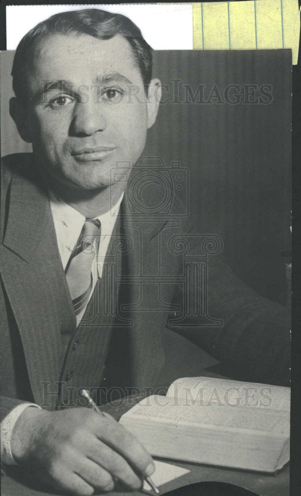 Press Photo Person wears suit reads book holds pen sits - Historic Images