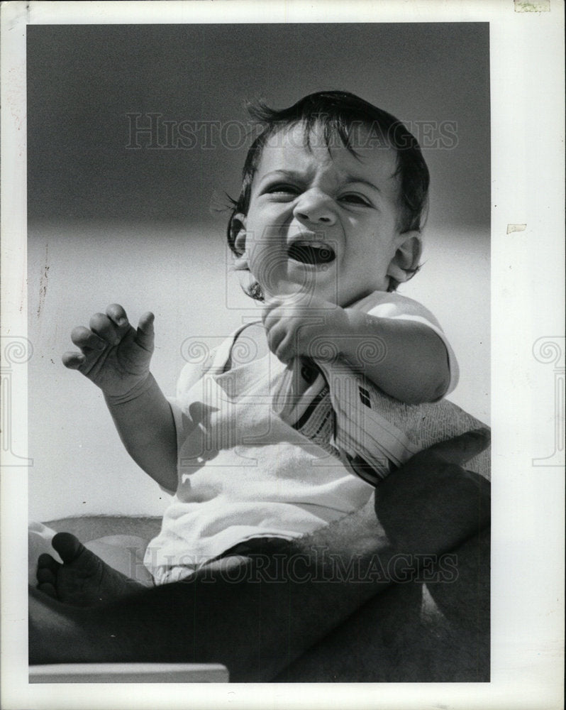 1989 Press Photo Baby Boy Crying Holds Newspaper - Historic Images