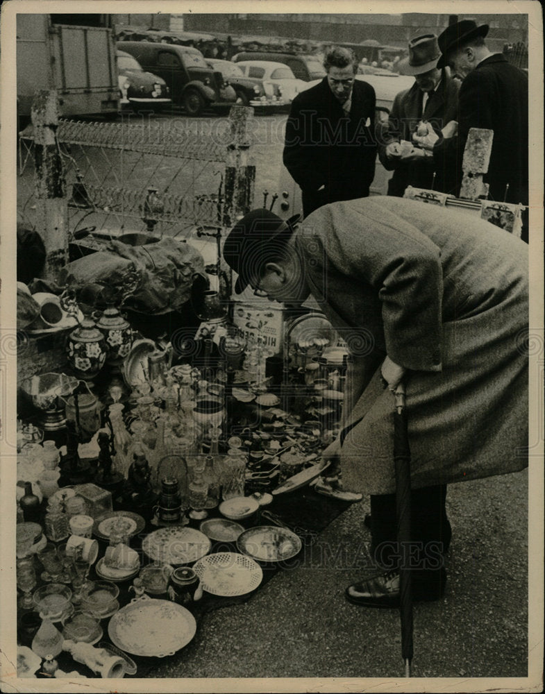 Press Photo man kneels cloth full chinaware - Historic Images