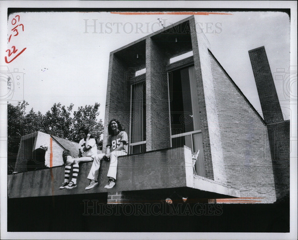 1976 Press Photo A girl and a boy sitting on a building - Historic Images