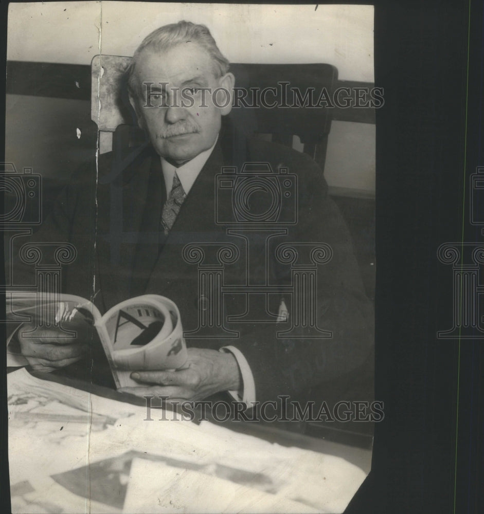 1924 Rev HC Lilaus sits opens book pose reads - Historic Images