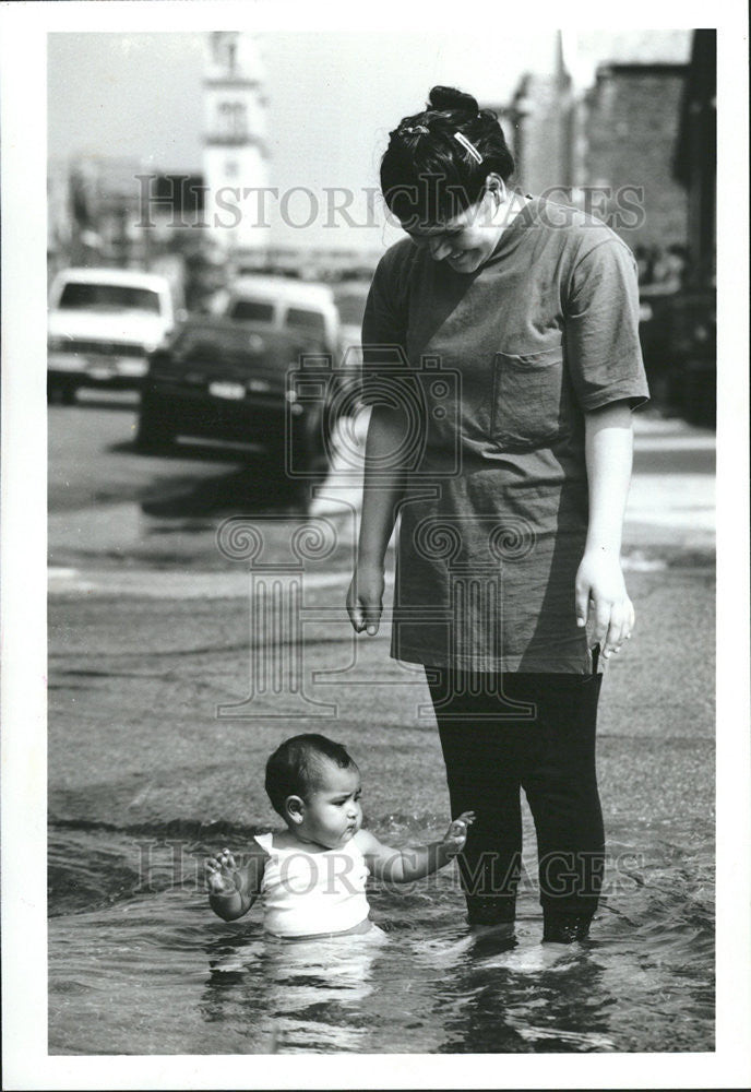 1991 Press Photo Elvia Montolla Maribel Salas flooded curb cup water spray - Historic Images