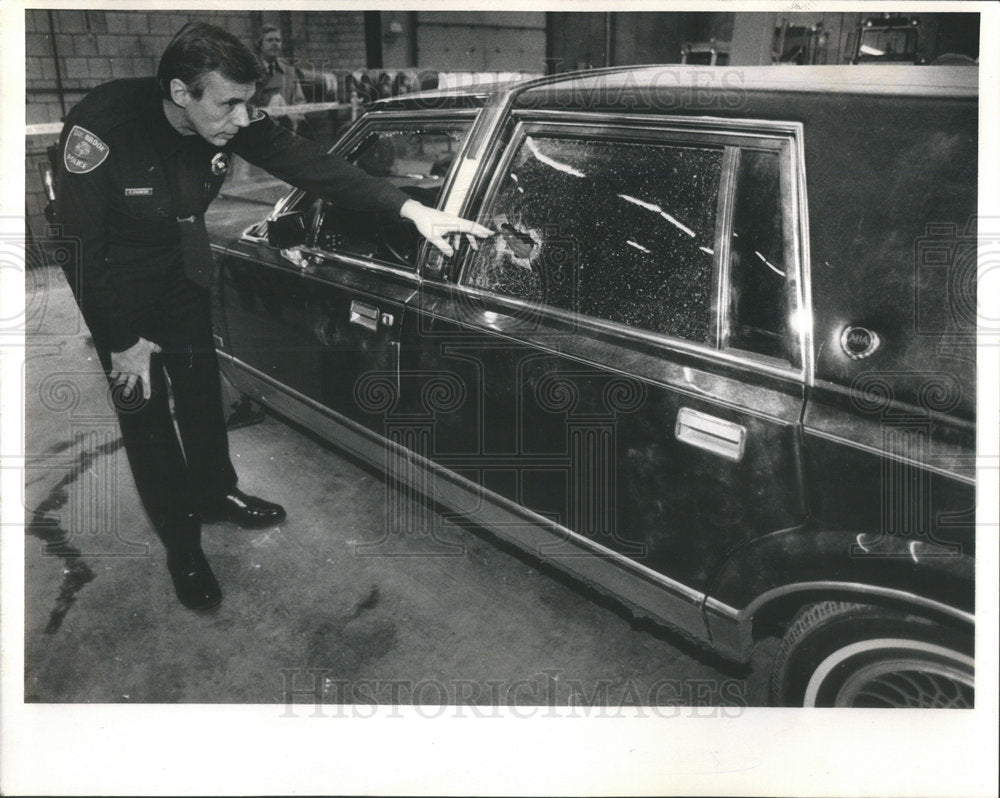 1988 Press Photo Oak Brook police officer Paul Stadwiser inspects the car in whi - Historic Images