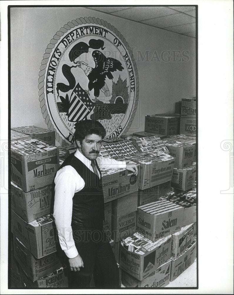 1982 Press Photo Laurence Mulcrone Deputy Director cigarette Ritter Story carton - Historic Images