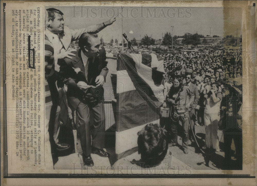 1972 Alabama Gov. George Wallace Ducks Behind Barrier at Rally - Historic Images