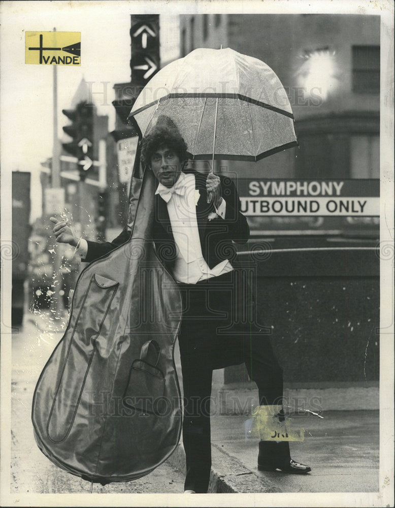 1975 Press Photo Actor Sand Holding Cello In Case Waiting For Taxi Umbrella - Historic Images