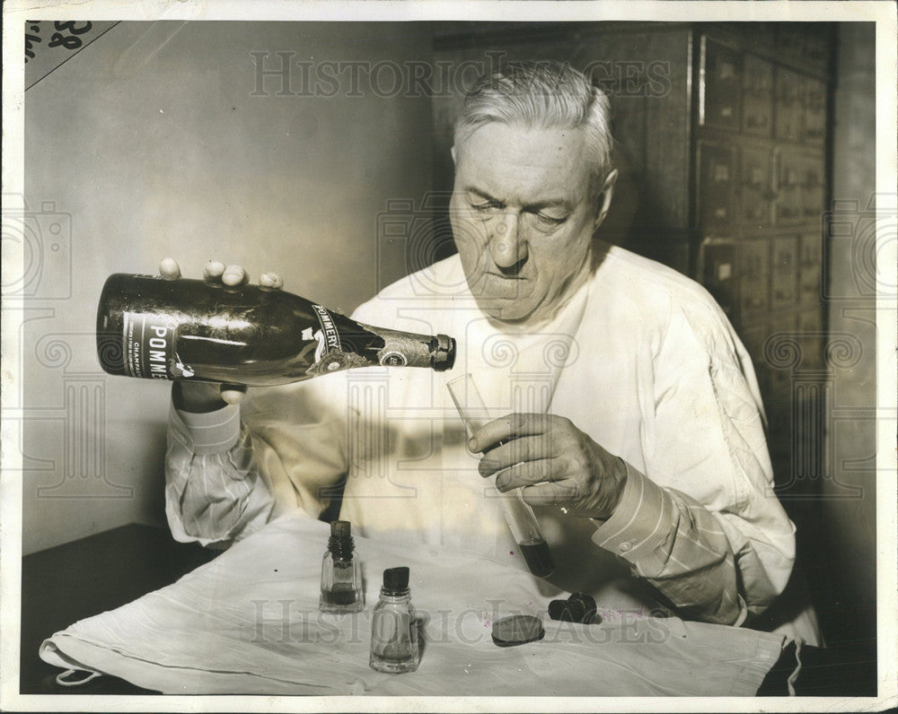 1942 Press Photo Dr. William McNally tests contents poison champagne bottle - Historic Images