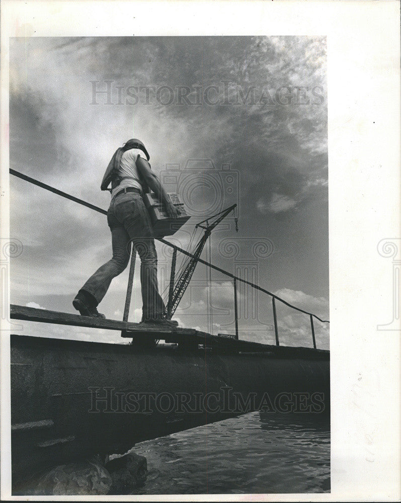 1977 Press Photo Worker Loads Supplies on Barge Prior to Start Up of Days Work - Historic Images