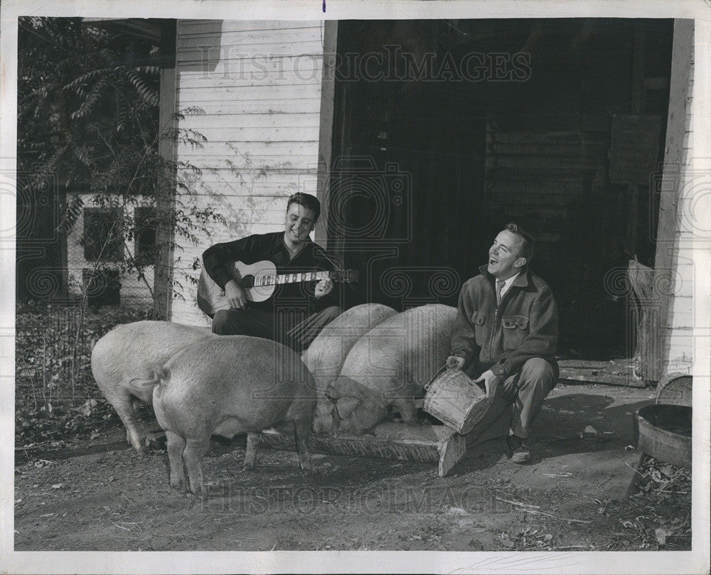 1950 Press Photo Hots Michels Plays Guitar As Hal White Sings While Feeding Pigs - Historic Images