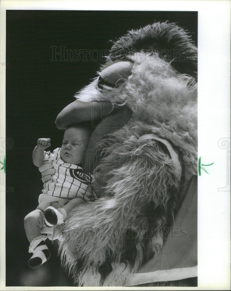 1983 Press Photo Chicken holding a baby at a Cubs' game. - Historic Images