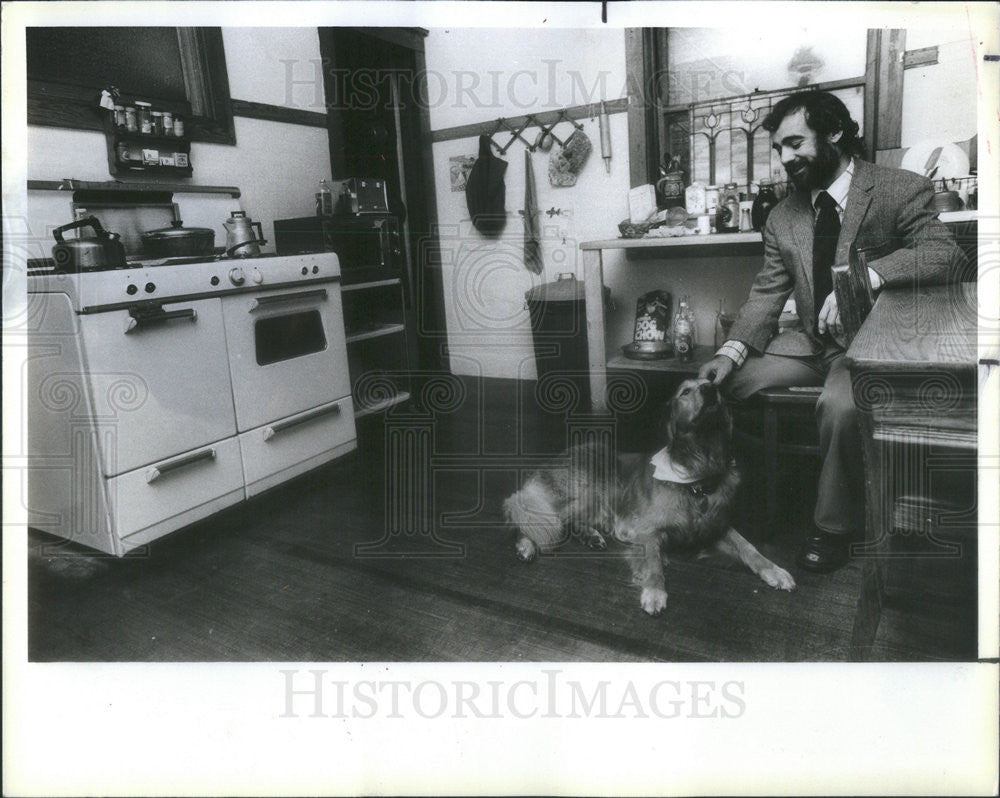 1984 Press Photo Rev Michael McConnell sitting at his kitchen &amp; dog Magoo - Historic Images