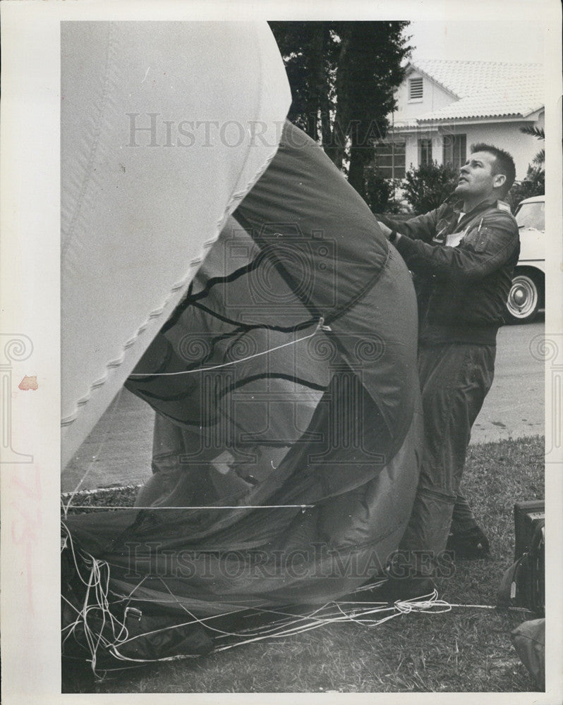 1964 Press Photo Capt C. W. Bradley untangles his parachute from a palm tree. - Historic Images
