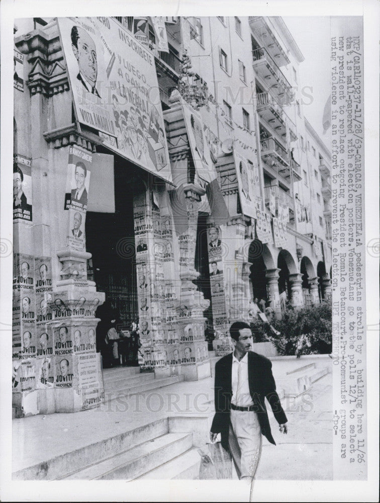 1963 Press Photo A Pedestrian strolls, Wall-papered with election posters - Historic Images