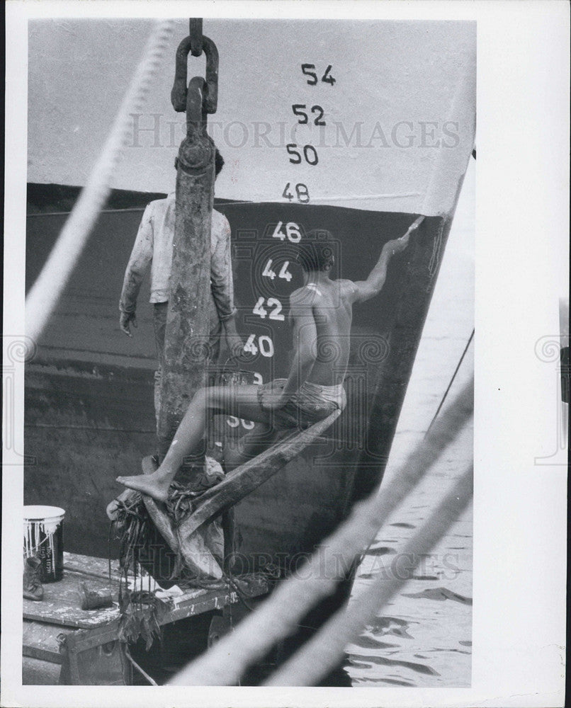 Press Photo Deck hand paints bow of boat from docks on Tampa waterfront - Historic Images