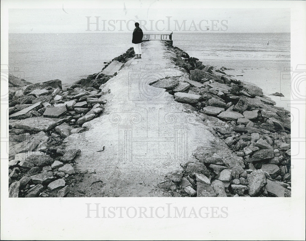 1983 Press Photo Woman Stand Sand Boulder Jetty Pass-A-Grill Beach Before Repair - Historic Images