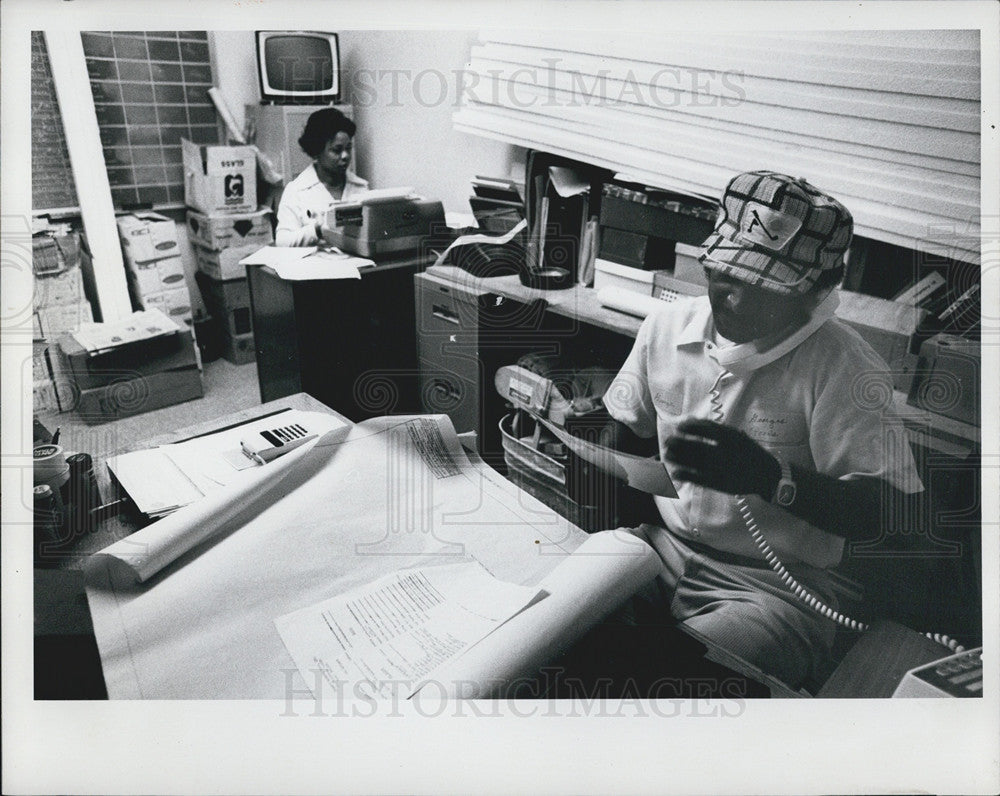 1977 Press Photo Man answers phone in small office - Historic Images
