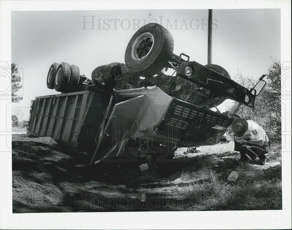 1987 Press Photo Sheriffs Deputy Surveying Damage of Over Turned Dump Truck - Historic Images