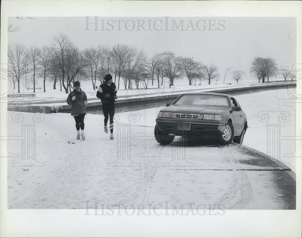 1989 Press Photo Jogger glances toward a car hanging on North Avenue Beach - Historic Images