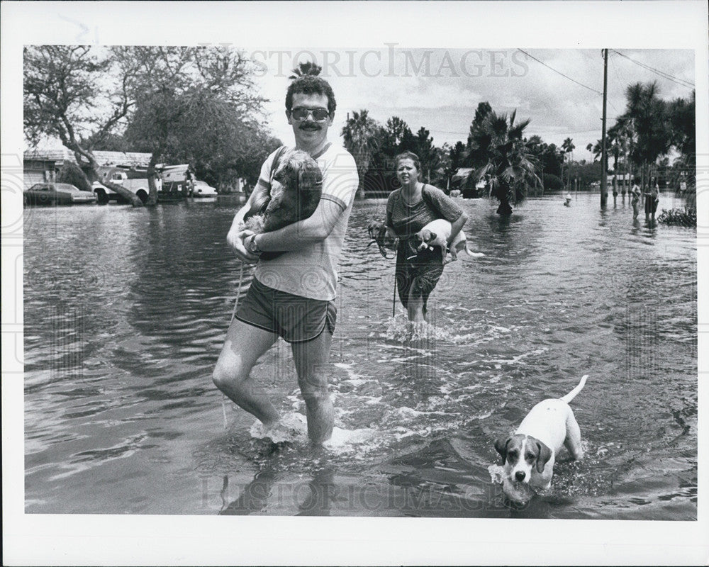 Press Photo A Man And A Woman Flee Storm-Related Flood With Dogs In Hand - Historic Images