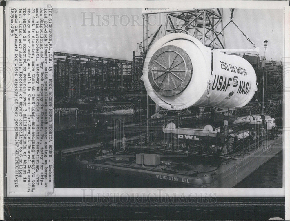 1965 Press Photo Workmen load solid propellant rocket motor casing on barge - Historic Images