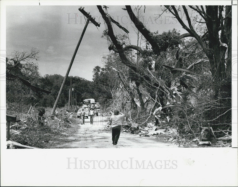 1987 Press Photo A woman wanders down tornado-ravaged road - Historic Images