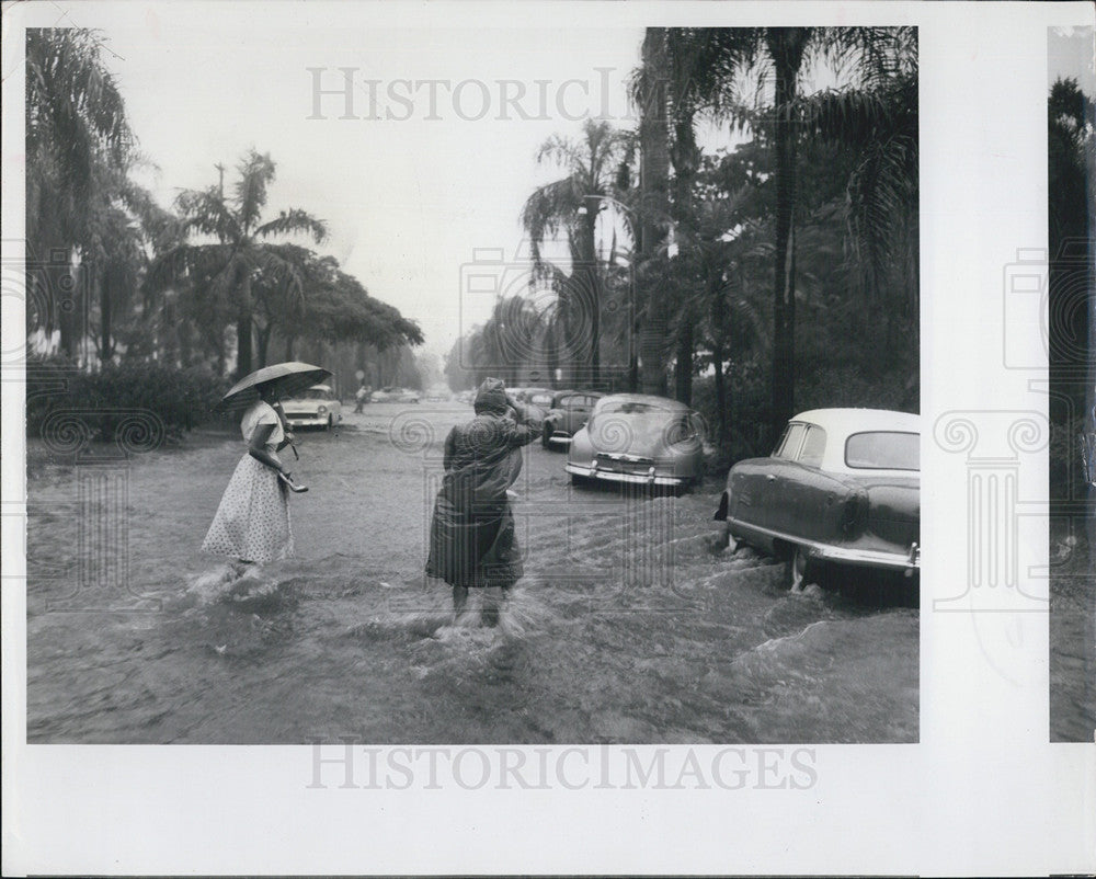 Press Photo Women Cross Flooded Road Rain Storm - Historic Images