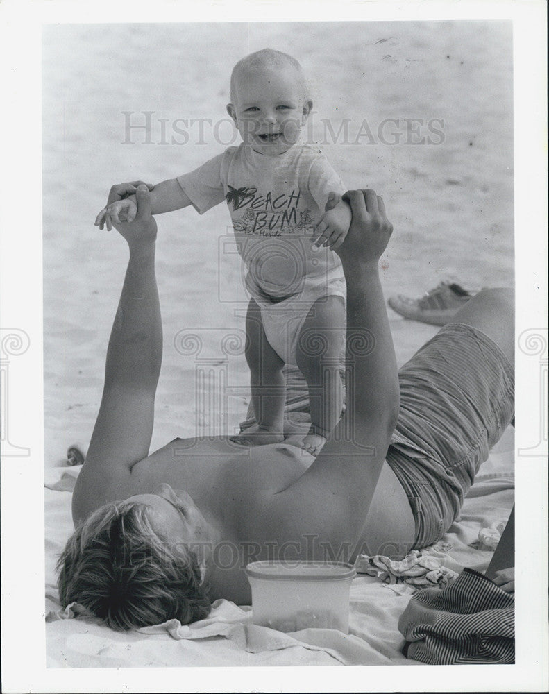 1987 Press Photo Clearwater Beach Kevin Downey Lifting Son Bryan - Historic Images