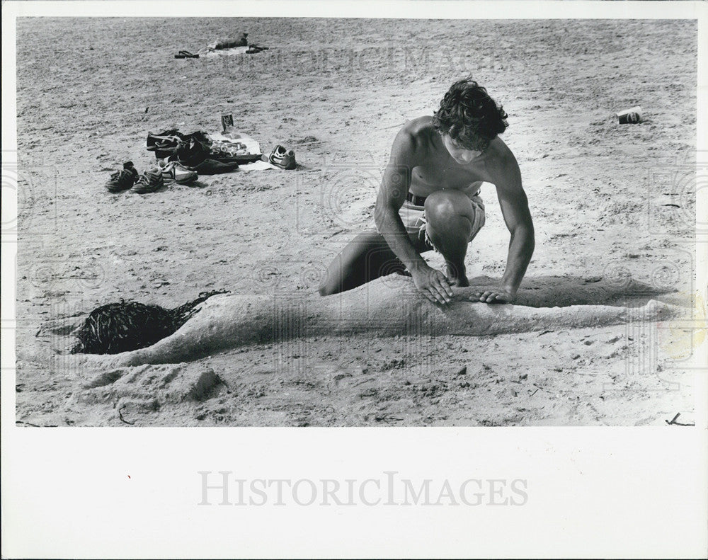 1981 Press Photo Man Makes Tanning Girl from Sand In Gulfport Beach - Historic Images