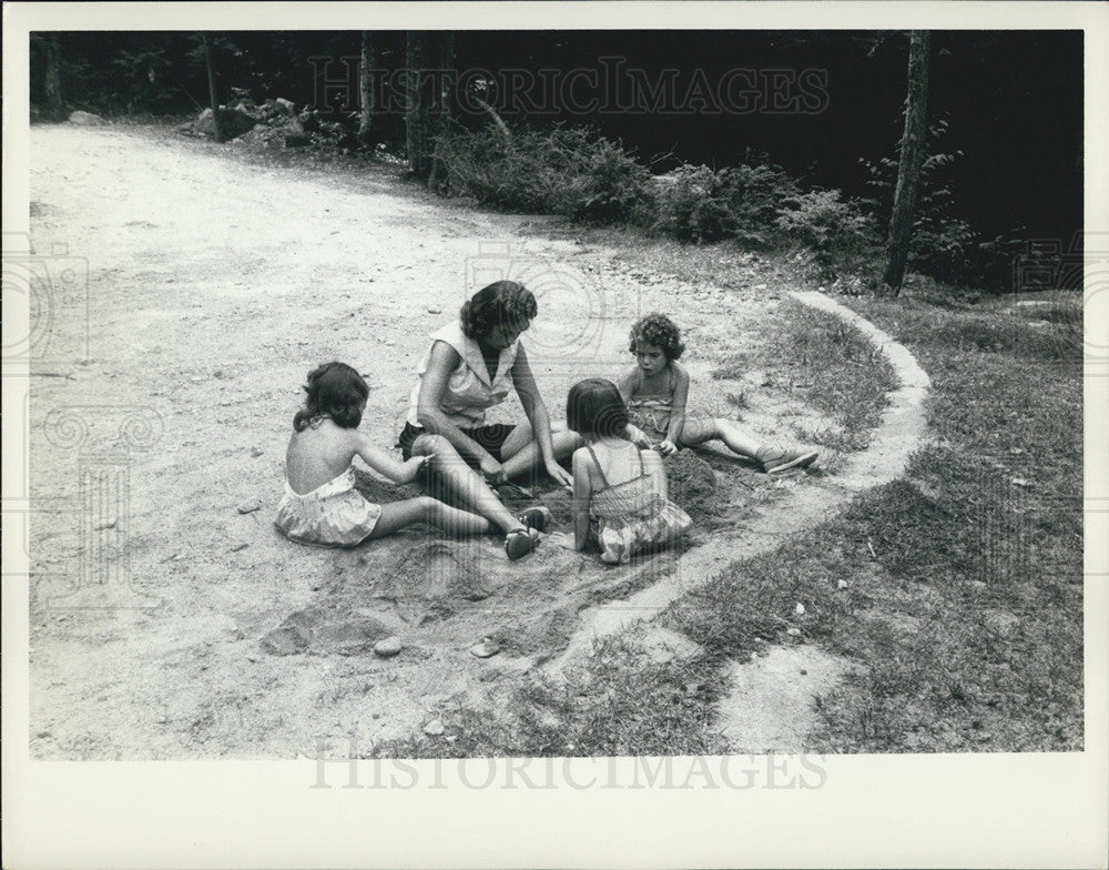 Press Photo Three girls And Their Mom Dig In The Sand - Historic Images