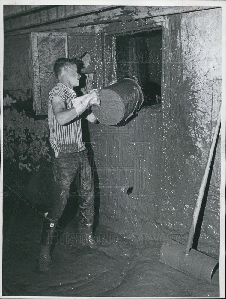 1965 Press Photo Earl Dykes throwing mud out of a flooded basement for clean up - Historic Images