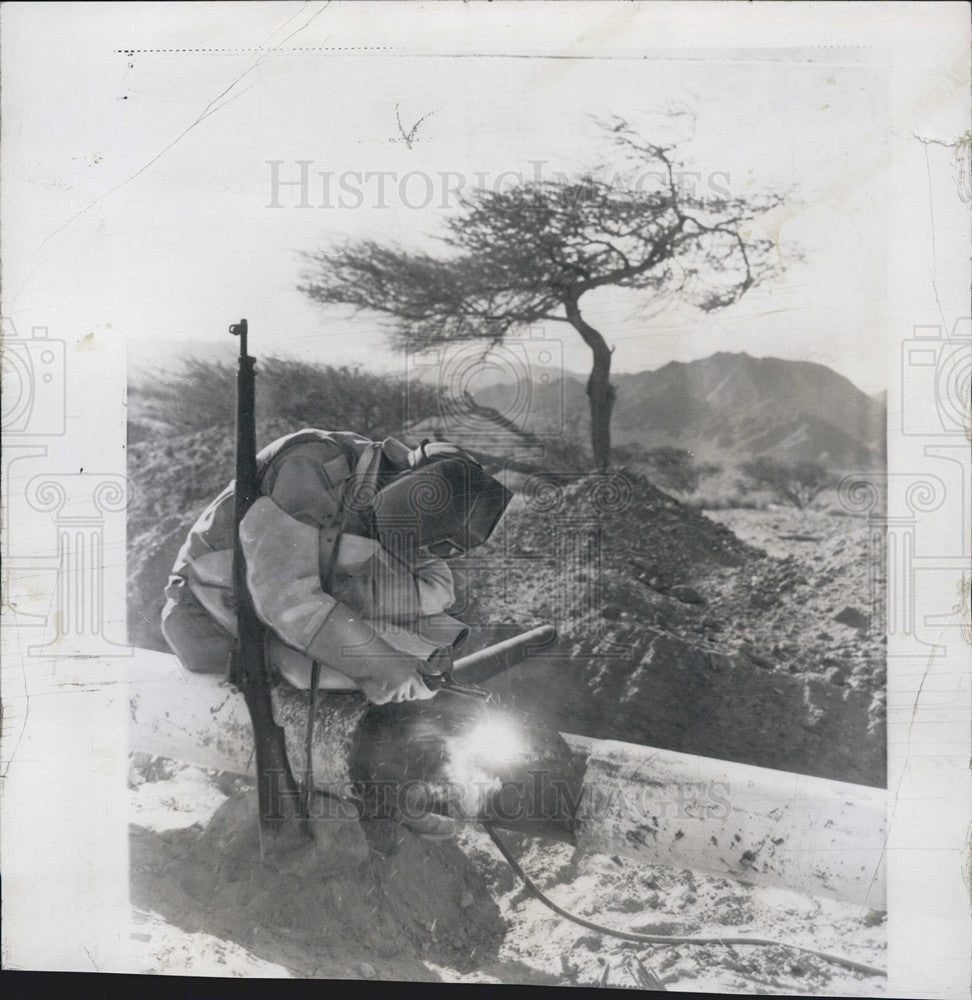 1956 Press Photo Armed Israeli Welder Works on Pipeline - Historic Images