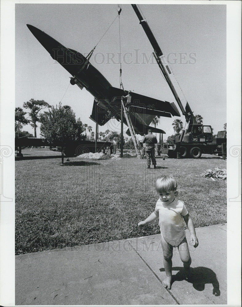 1985 Press Photo Angela Stager toddles in front of F-11 Navy jet on display - Historic Images