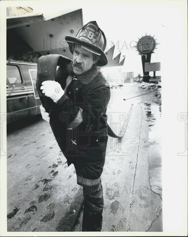 1985 Press Photo Fireman Carl Schuyler carries hose after fire from Quality Inn - Historic Images